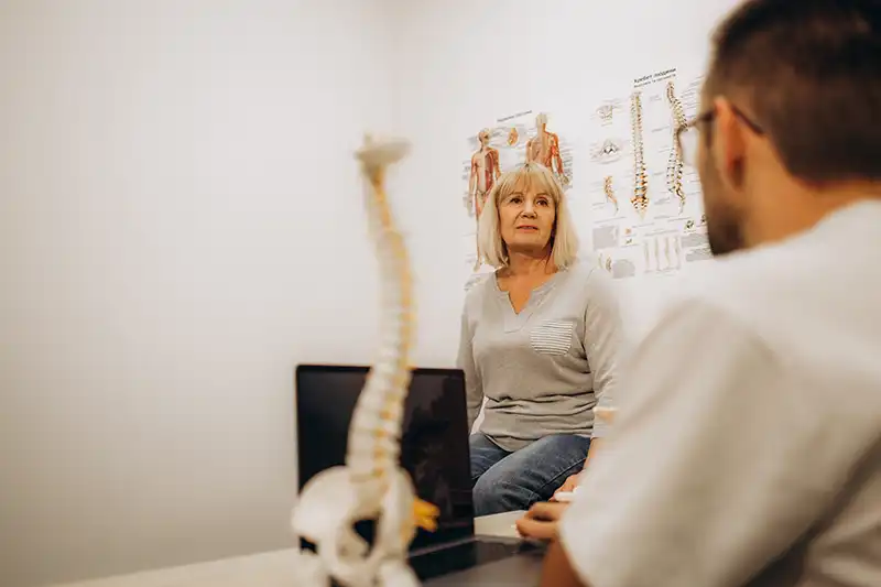 senior woman sitting with chiropractor