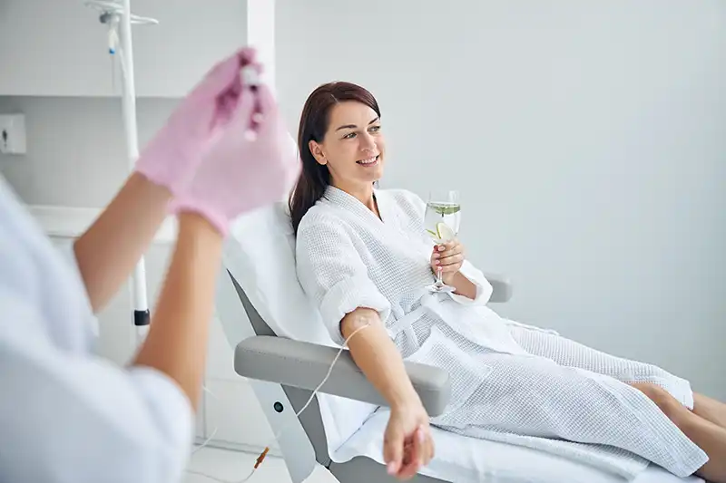 smiling woman getting iv drip therapy