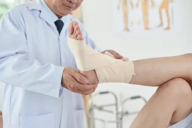 doctor wrapping sprained ankle at urgent care